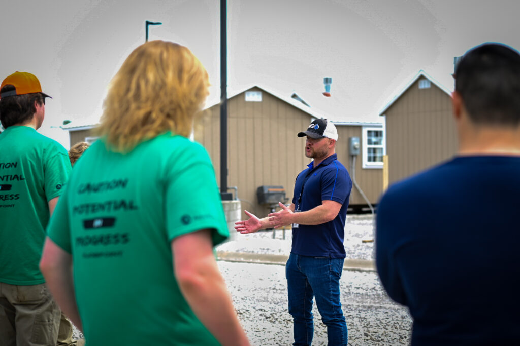 Students listen to the tour guide explain processes outside of model homes