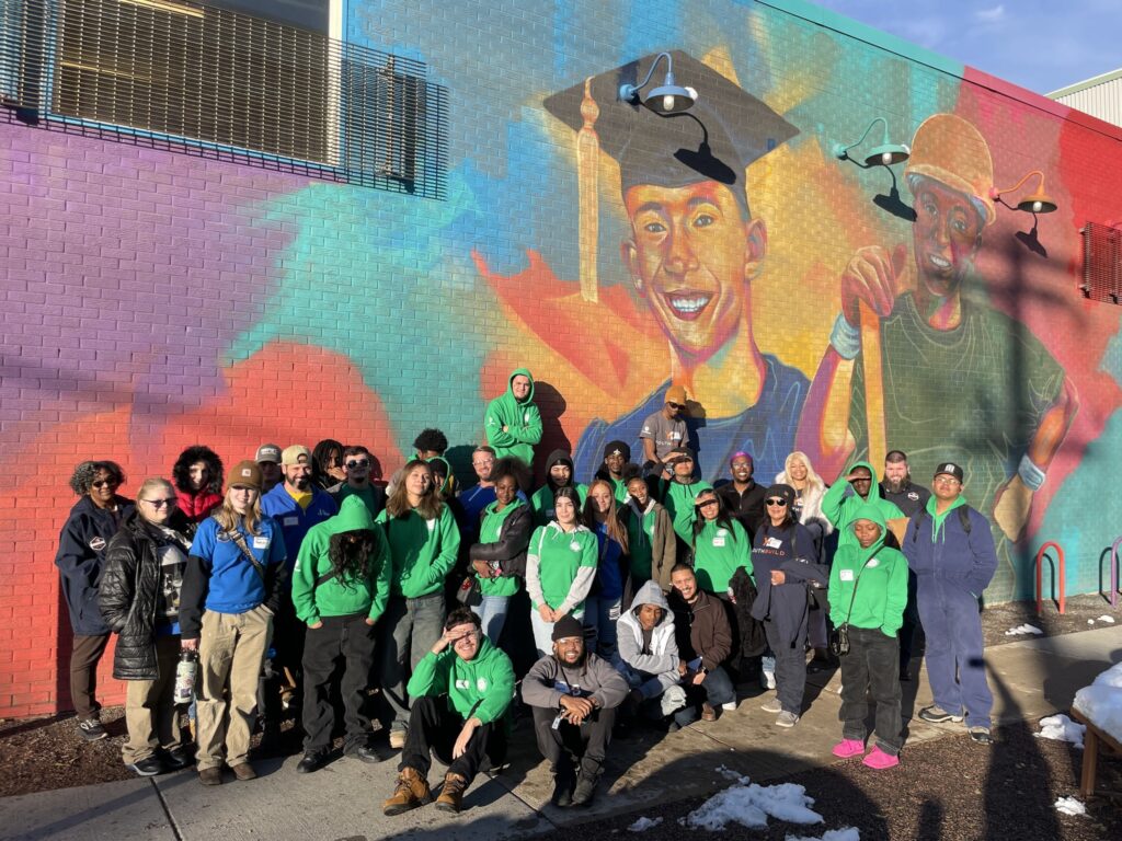 Students pose together outside of a brightly colored mural.