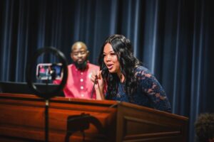 A young woman leans in to speak into a microphone